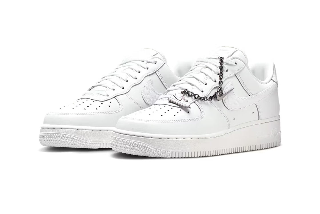 Pair of white Nike Air Force 1 low-top sneakers with lace-up and chain detail