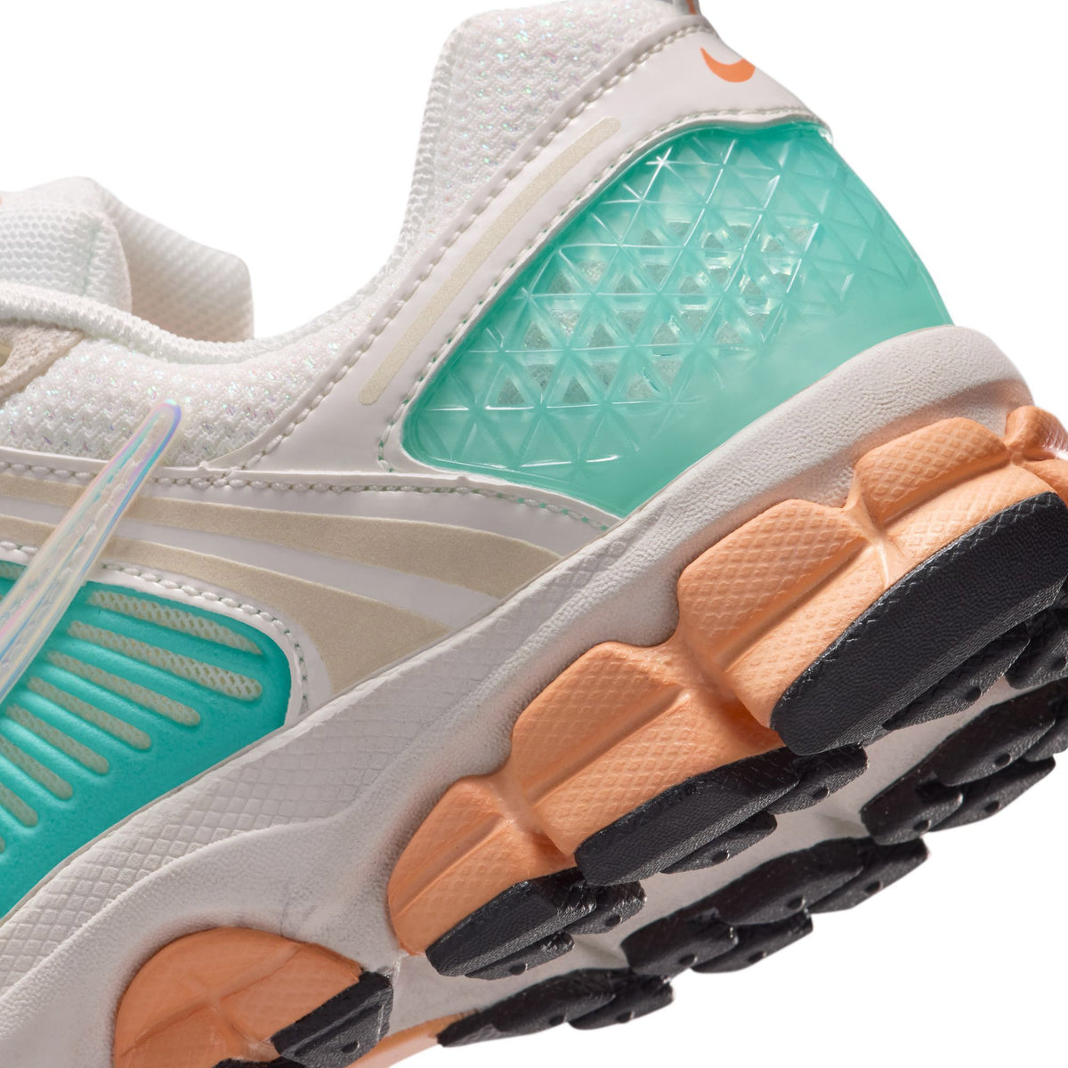 Kids' Nike shoe upper close-up: teal translucent panel, orange grip pods on sole.