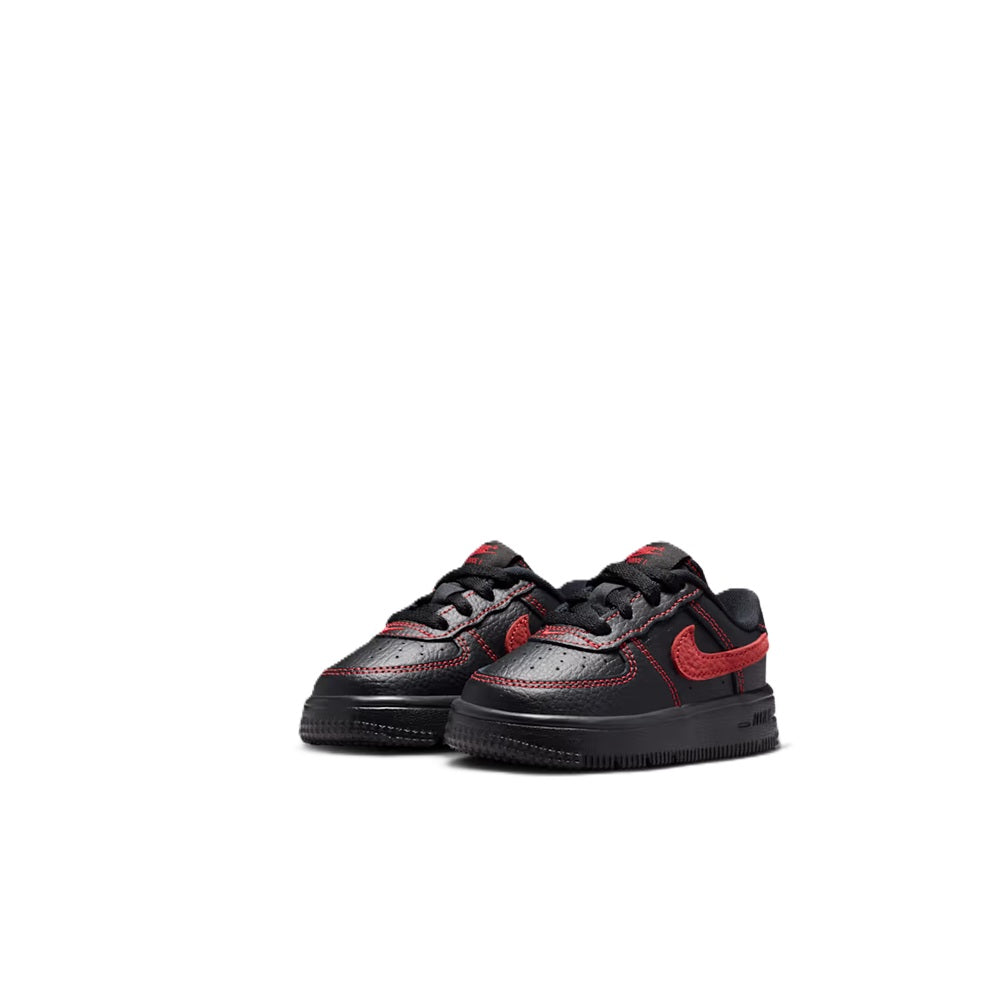 Toddler low-top lace-up sneakers in black with red swoosh, shown in pair view.