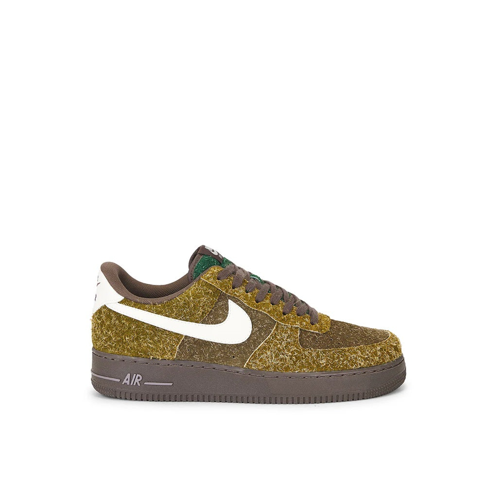 Low-top sneakers with gold patterned upper, white Nike swoosh, and dark rubber sole