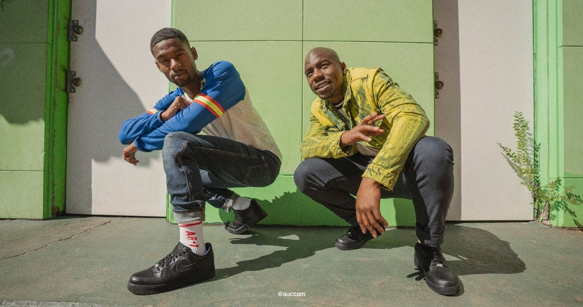Black low-top sneakers worn by two people, lace-up style
