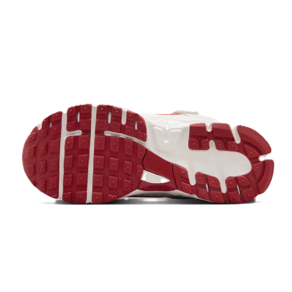 Kids' Nike Vomero 5 SE outsole view, red rubber traction pods on white sole.