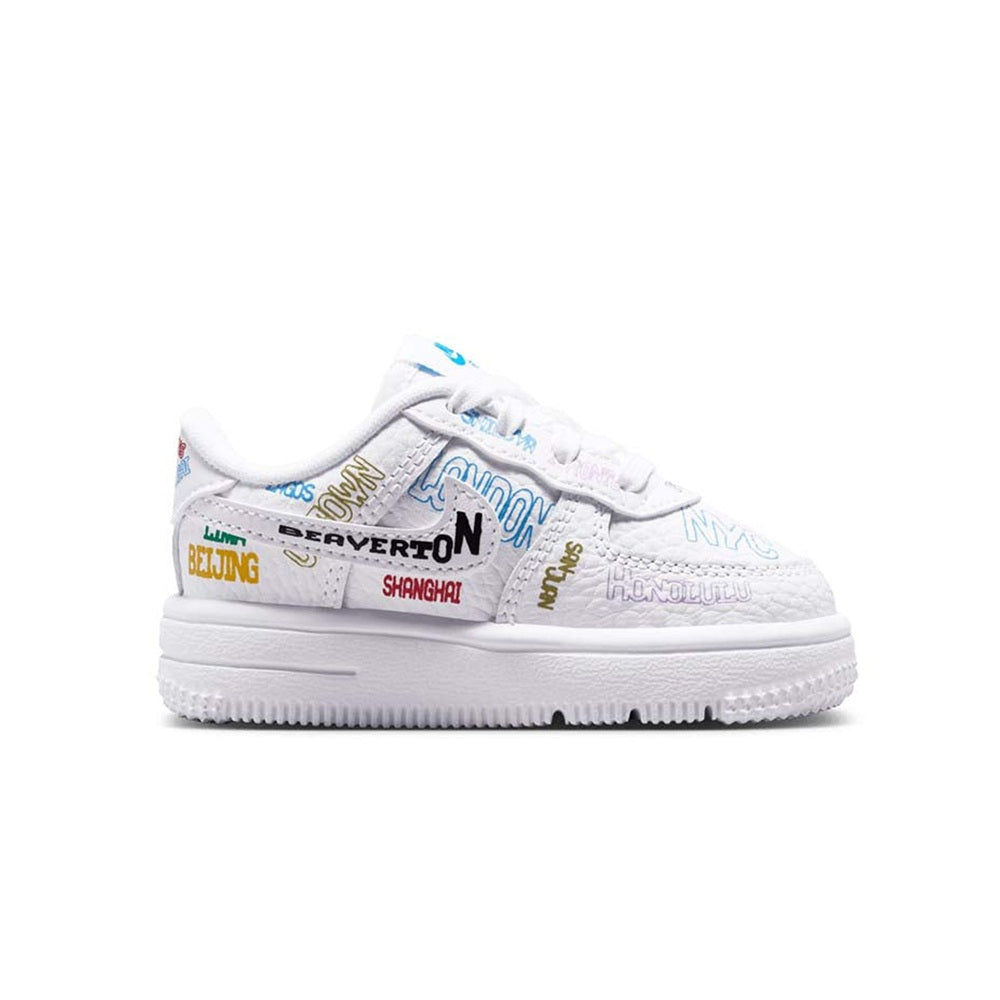 Toddler low-top Nike Air Force 1 sneakers in white with colorful city text.