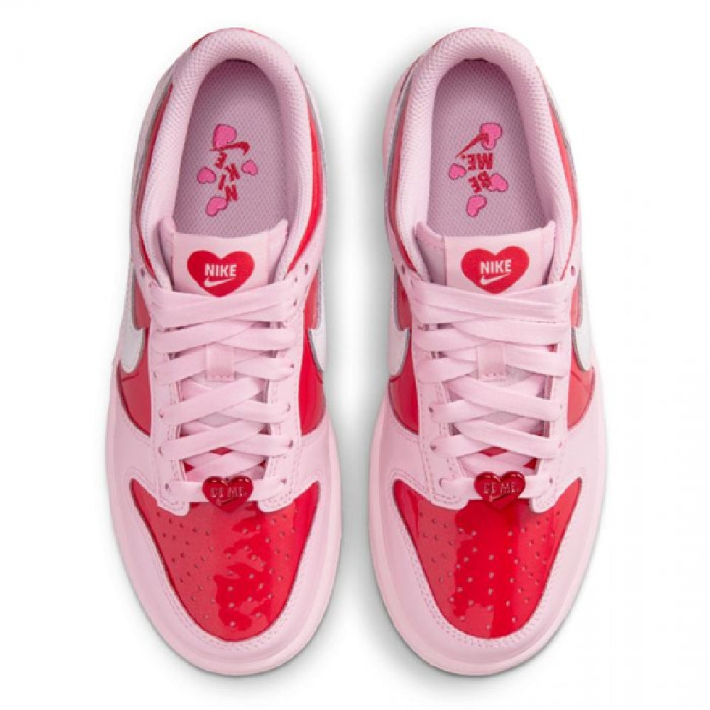Pink low-top sneaker pair showing Nike tongue branding and lace-up eyelets.