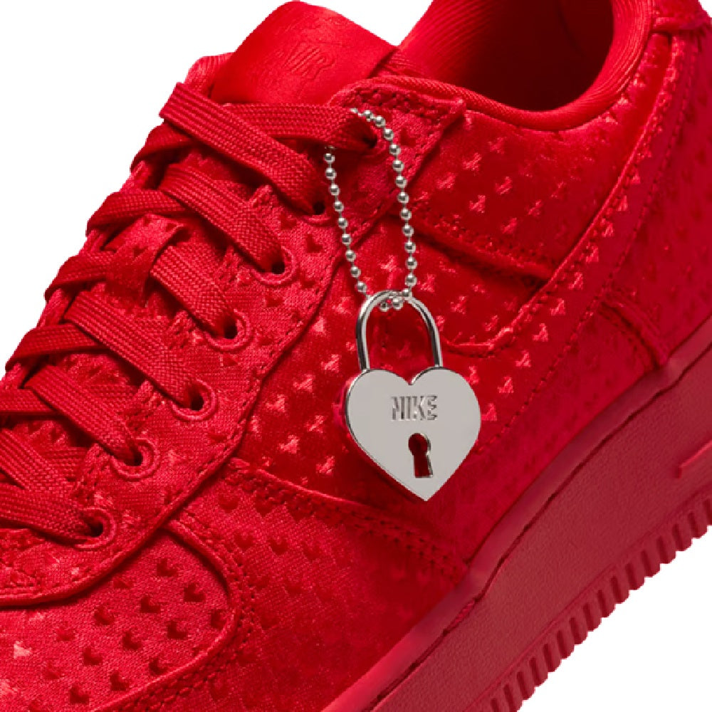 Red Nike sneakers with heart-shaped padlock charm detail on lace-up upper