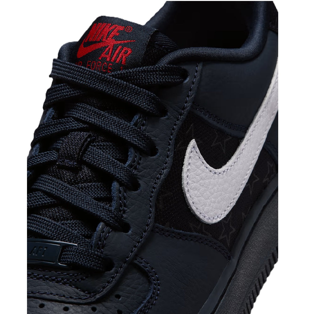 Nike Air Force 1 close-up, dark laces and white swoosh with red AIR on tongue.
