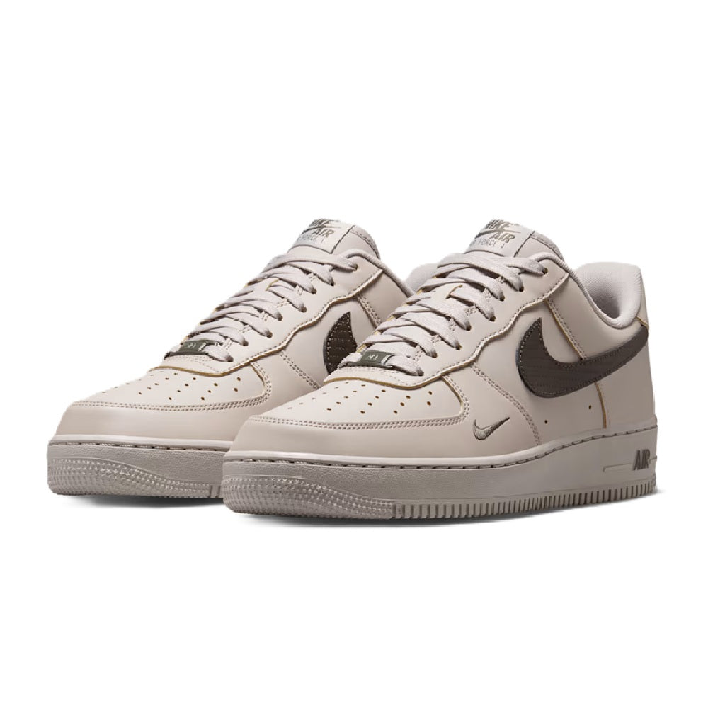 Pair of Nike Air Force 1 low-top sneakers in light gray and off-white, front toe view