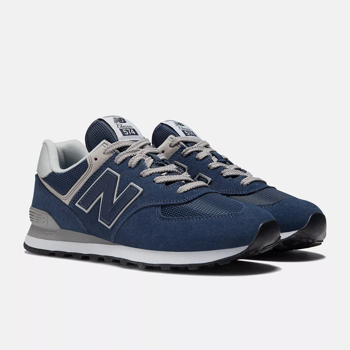 New Balance 574 sneakers, navy blue with white accents and lace-up front, angled