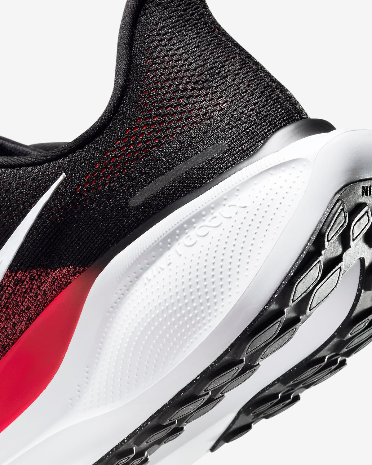 Black running shoe with red knit pattern and white midsole with tread detail