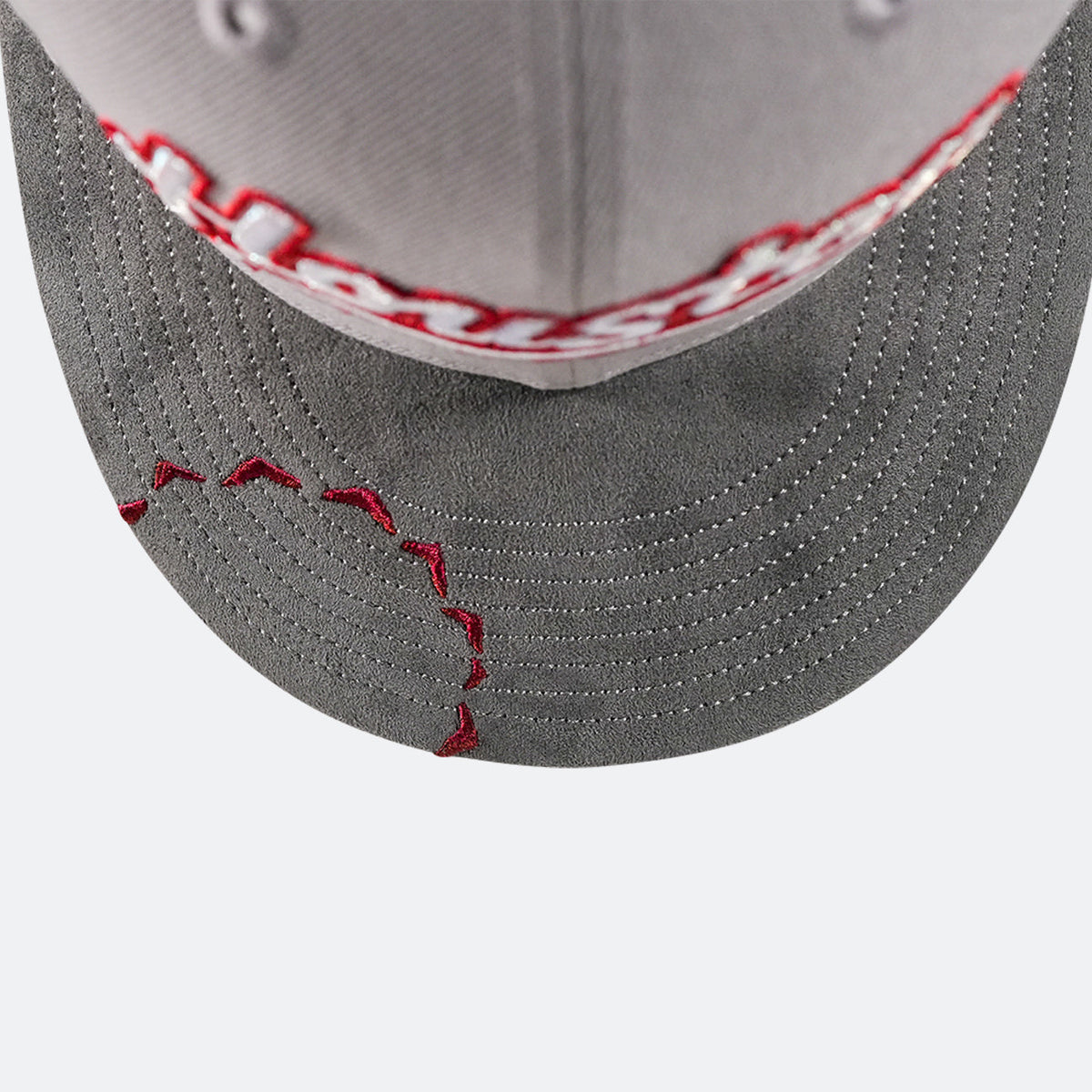 Close-up of grey crown and dark brim with red stitching and embroidered details